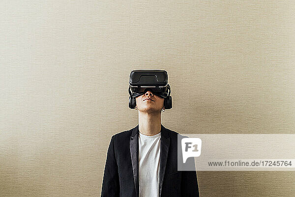 Geschäftsfrau mit Virtual-Reality-Headset vor einer Wand stehend