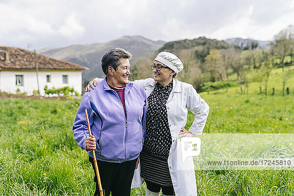 Smiling woman looking at senior mother while standing on grass