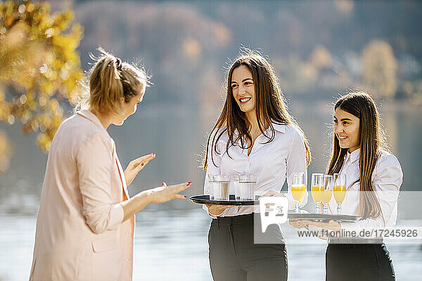 Female event planner instructing waitress holding drink trays