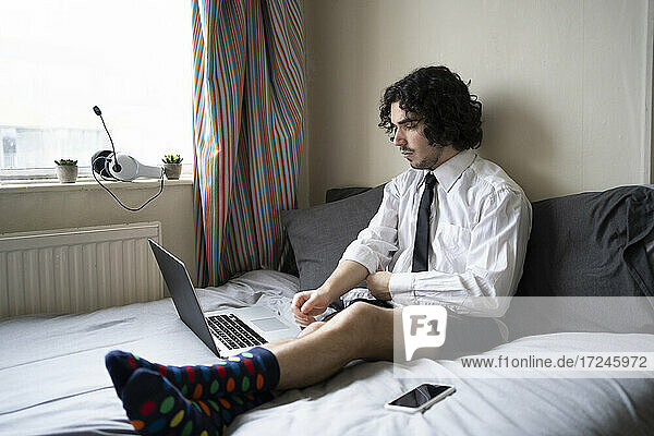 Businessman working on bed in apartment