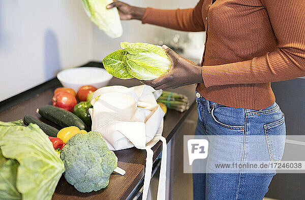 Mittlere erwachsene Frau  die zu Hause die Lebensmittel auf dem Küchentisch kontrolliert