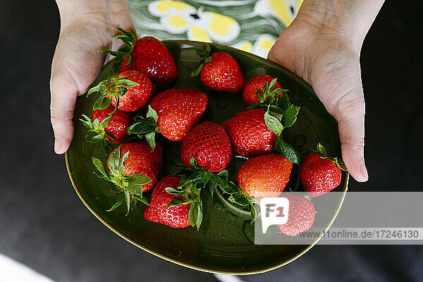 Frau hält Teller mit frischen Erdbeeren