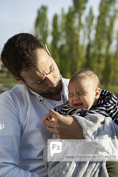 Vater tröstet weinenden kleinen Jungen im Park