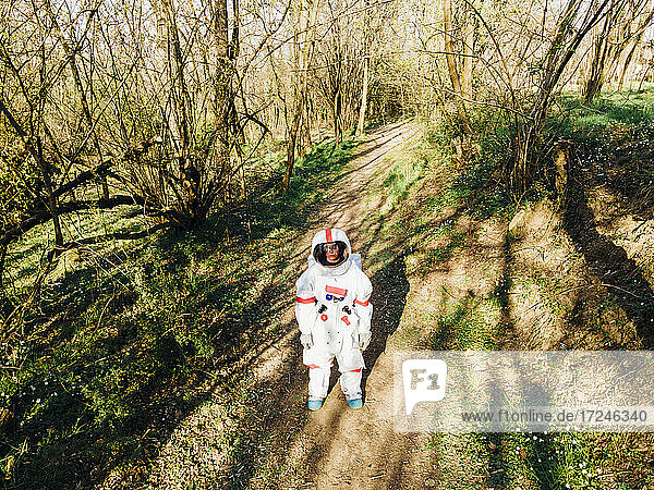 Astronautin im Raumanzug auf einem Waldweg