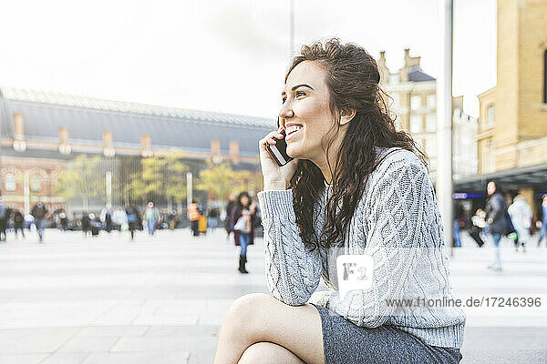 Lächelnde Geschäftsfrau  die in der Stadt mit einem Mobiltelefon spricht