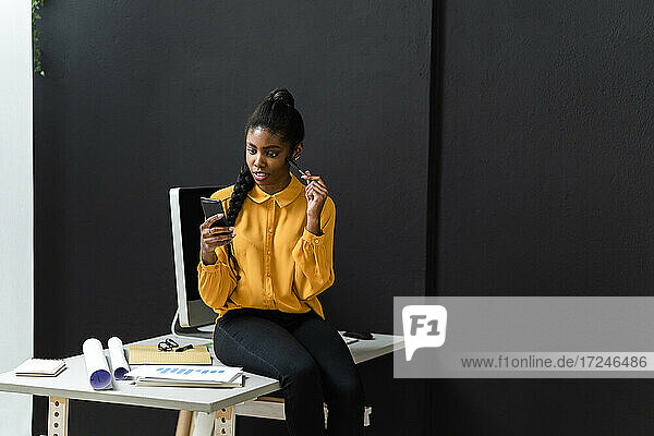 Geschäftsfrau schaut im Studio auf ihr Mobiltelefon