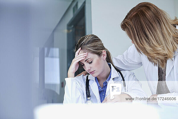 Ärztin tröstet traurigen Kollegen im Krankenhaus