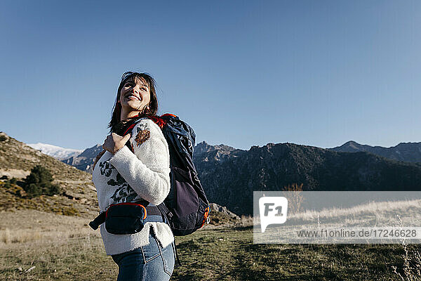 Glückliche Frau mit Rucksack am Berg stehend