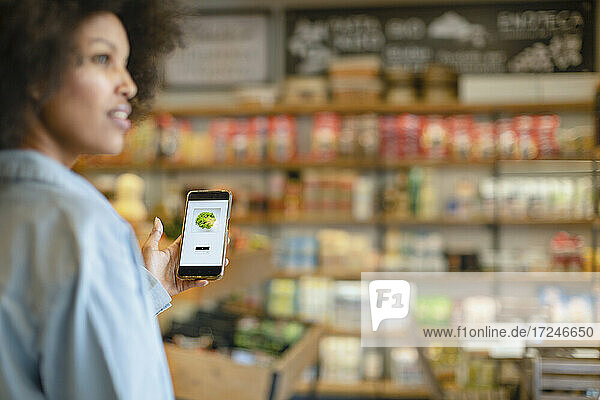 Frau kauft Gemüse über eine mobile Anwendung im Supermarkt
