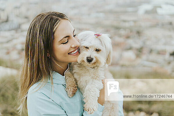 Beautiful woman smiling while embracing dog