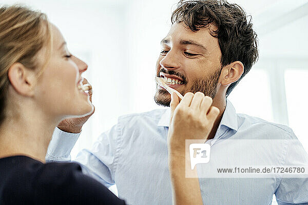 Young couple brushing each other's teeth at home