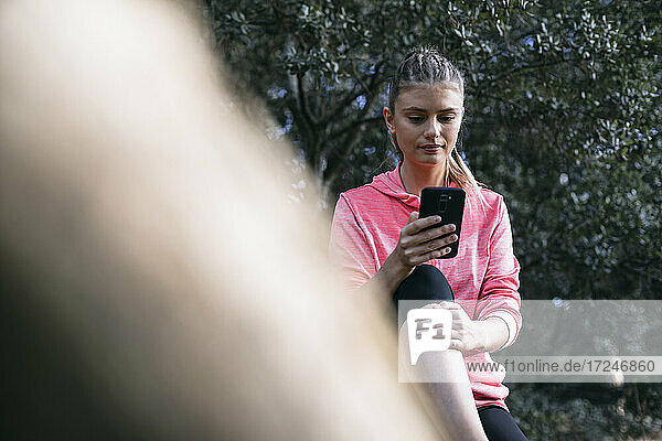Sportlerin benutzt Smartphone im Wald
