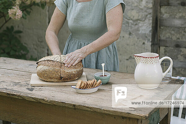 Reife Frau prüft Laib Brot im Hinterhof