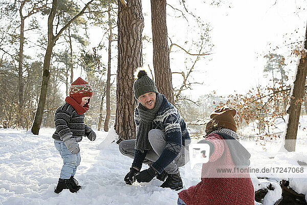 Father playing with sons on snow during winter