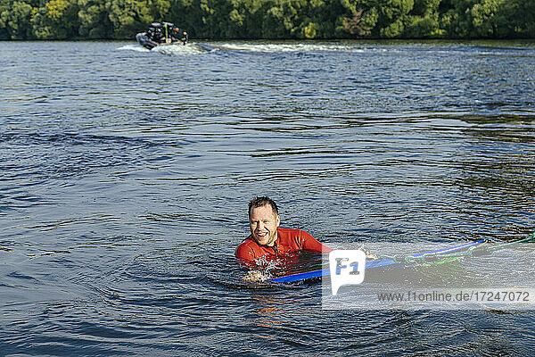 Männlicher Surfer lächelt beim Schwimmen im Fluss Moskva in die Kamera