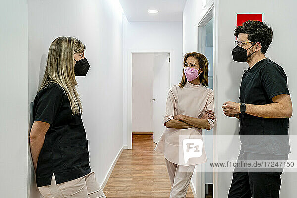 Zahnärztin im Gespräch mit männlichem und weiblichem Gesundheitspersonal in der Klinik während der Pandemie