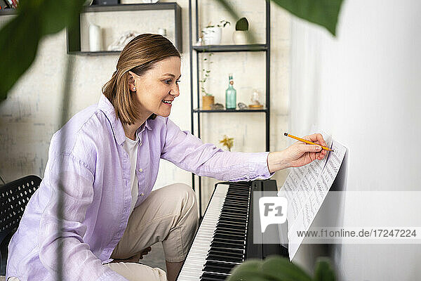 Lächelnde Frau mit Musiknote beim Lernen zu Hause