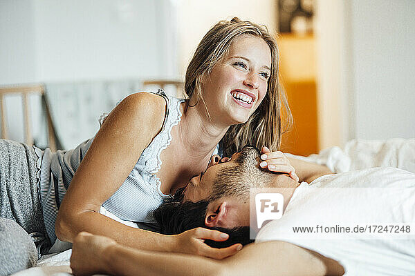 Cheerful young couple lying on bed at home