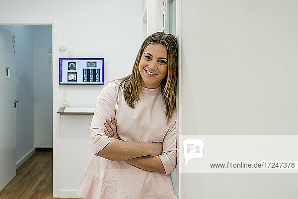 Lächelnde Frau lehnt an der Wand einer medizinischen Klinik