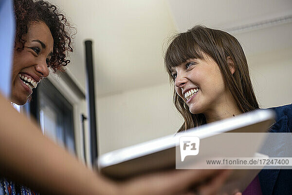 Lächelnde Unternehmerinnen schauen sich im Büro an