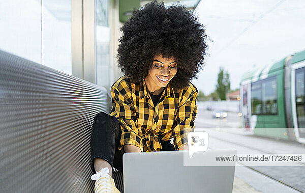 Lächelnde Frau mit Laptop am Bahnhof
