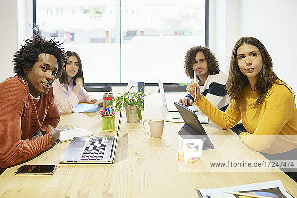 Multi-ethnische männliche und weibliche Fachkräfte sitzen am Konferenztisch im Büro