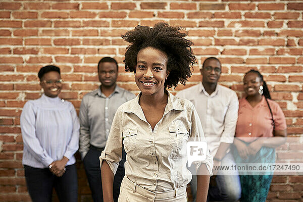 Afro businesswoman with male and female coworkers standing in background at office