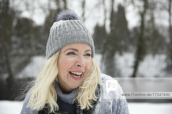 Smiling senior woman with knit hat looking away during winter