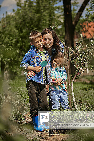 Smiling mother with son and daughter in back yard