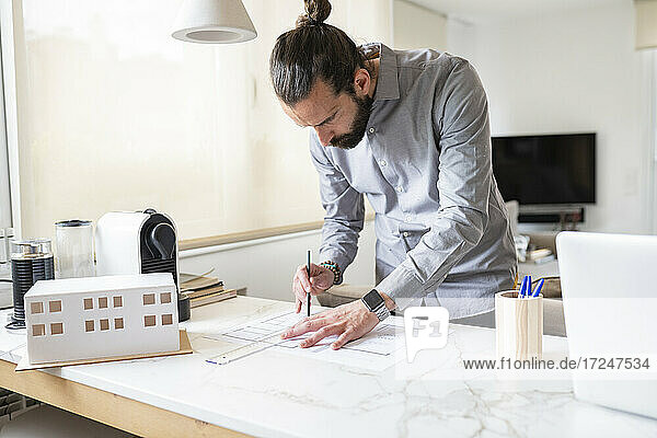 Male architect designing construction plan while working at home