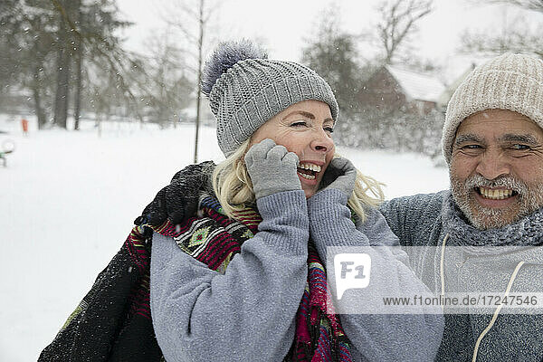 Cheerful woman and man in warm clothing at park during winter