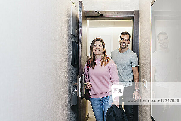 Mittleres erwachsenes Paar lächelt beim Betreten eines Hotelzimmers