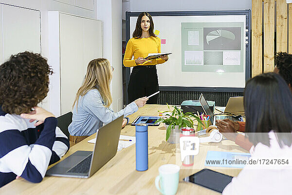 Weibliche Fachkraft  die über einen Projektionsschirm in einer Besprechung im Büro diskutiert