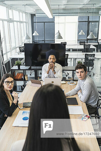 Männliche und weibliche Fachleute  die sich umsehen  und eine Geschäftsfrau  die während eines Treffens im Büro diskutiert