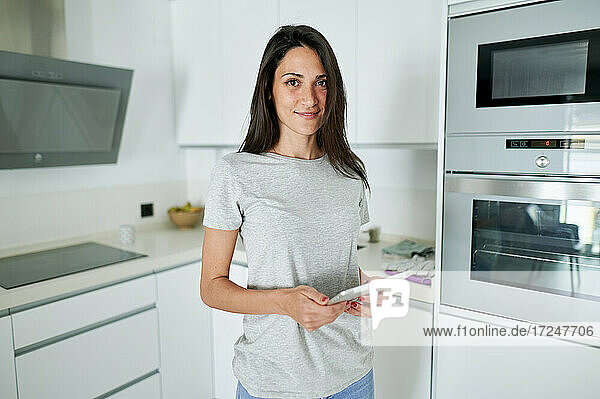 Lächelnde Frau mit digitalem Tablet in der Küche