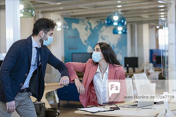 Male and female entrepreneurs doing elbow bump during pandemic at office