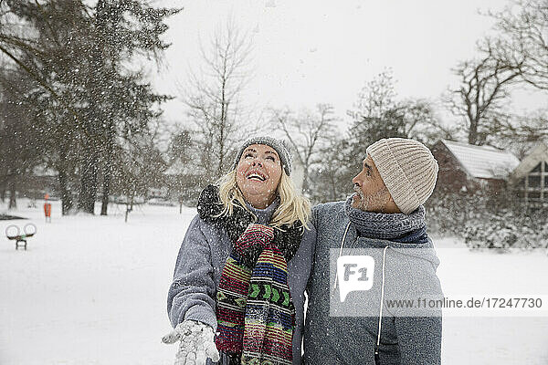 Glückliche Frau  die mit Schnee spielt  während sie im Park steht
