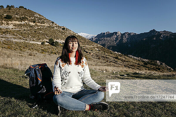 Junge Frau meditiert am Berg