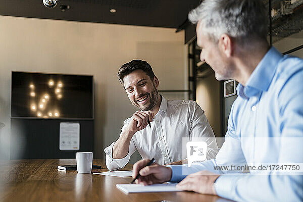Smiling business people with paper documents in board room meeting