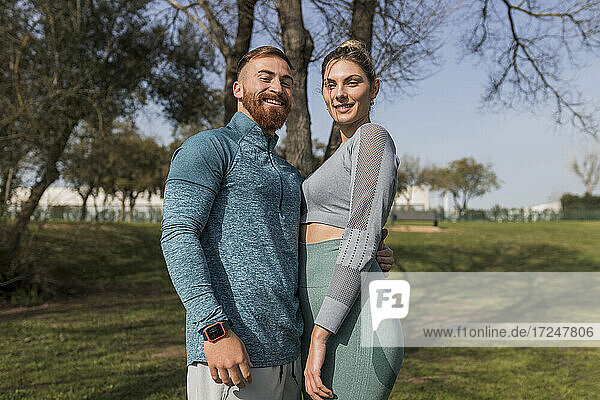 Lächelndes junges Paar im öffentlichen Park stehend