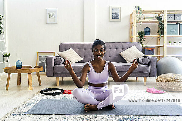 Lächelnde junge Frau  die zu Hause Yoga übt