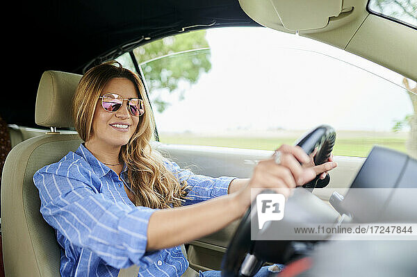 Mittlere erwachsene Frau lächelt beim Autofahren