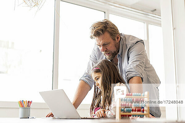 Mädchen lernt am Laptop mit einem Mann  der zu Hause steht