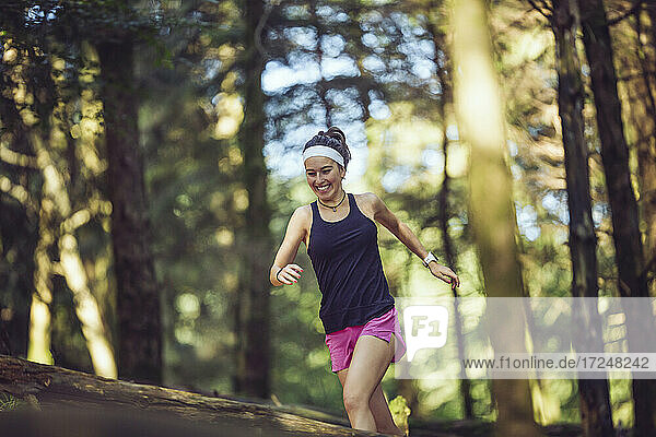 Smiling sportswoman running in forest
