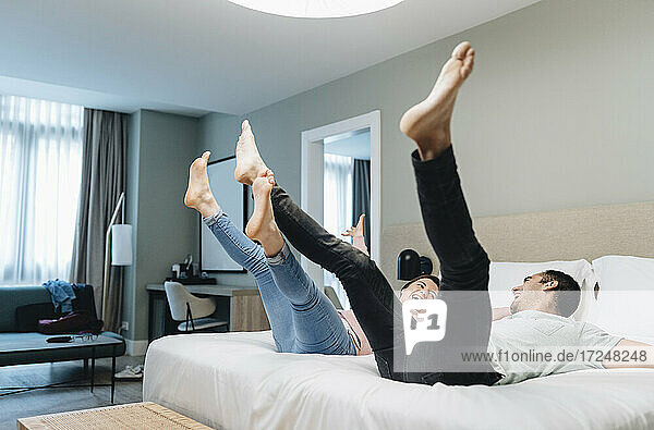 Unbeschwertes Paar hüpft auf dem Bett im Hotelzimmer