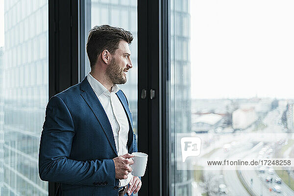 Geschäftsmann mit Kaffeetasse träumt Tag am Fenster bei der Arbeit Platz