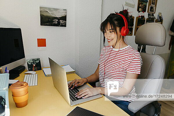 Frau mit Kopfhörern bei der Arbeit am Laptop im Heimbüro