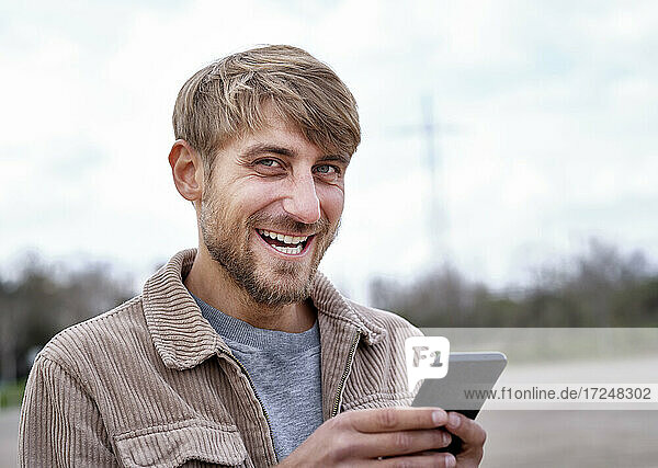 Smiling man with blond hair holding smart phone