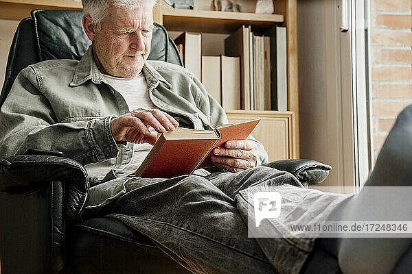 Älterer Mann liest zu Hause ein Buch