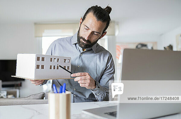Male professional explaining architectural model on video call at home